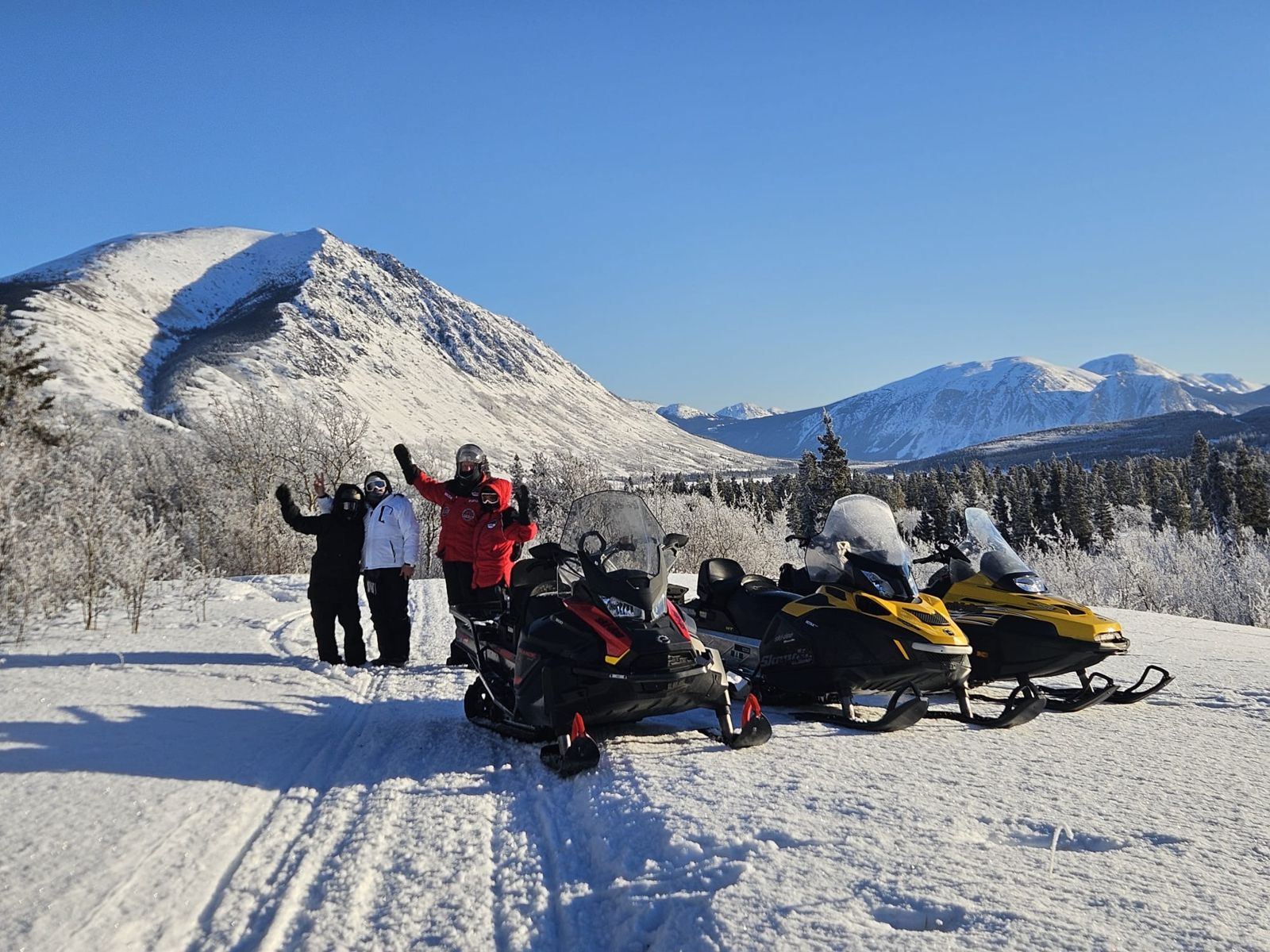 Groupe de voyageurs et leurs motoneiges au pied des montagnes