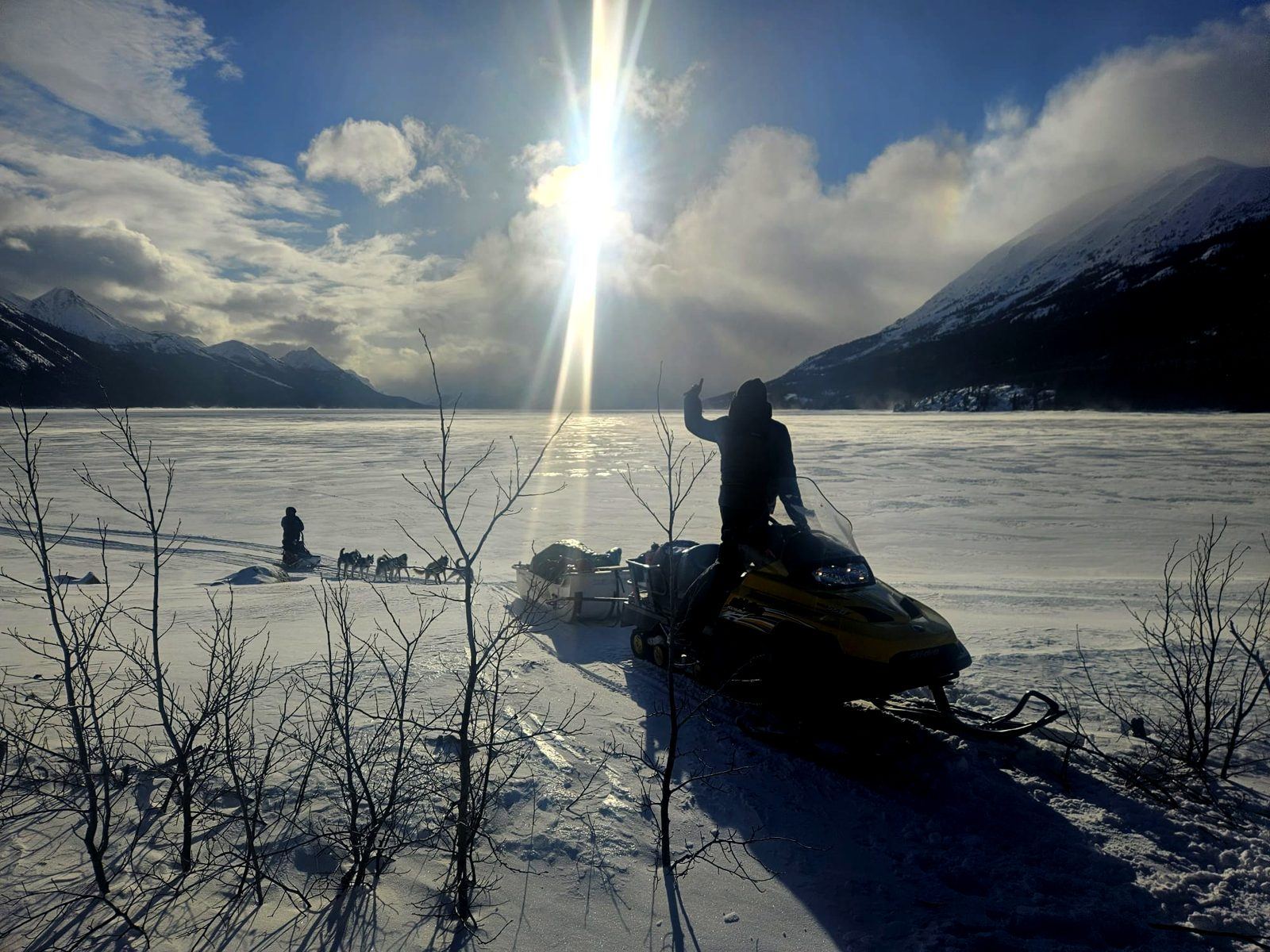 Motoneige et attelage de chiens sur un lac gelé, au Yukon
