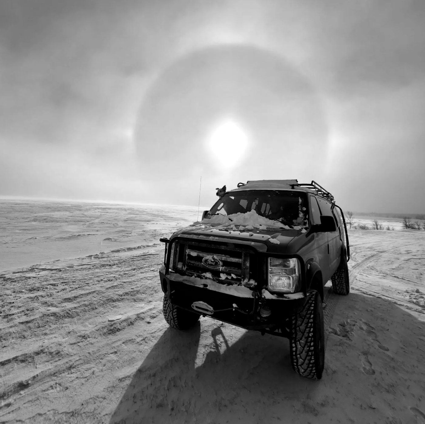 Expedition vehicle under a solar halo on the ice, in the Far North